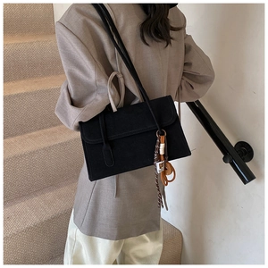 Model wearing a black matte shoulder bag with a silk scarf accent on a khaki blazer