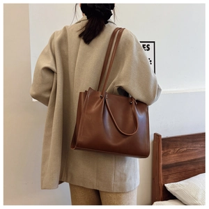 Detail view of a large brown tote bag with dual straps for daily commute style