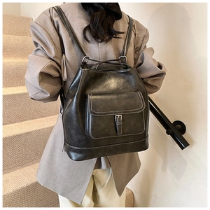 Close-up of black leather backpack with white stitching and front pocket flap detail