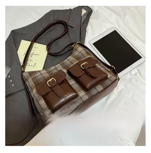 Detail view of British style checkered crossbody bag with two leather buckle pockets