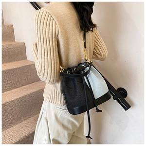 Detail of a color-block drawstring bucket bag featuring black and light blue fabric textures