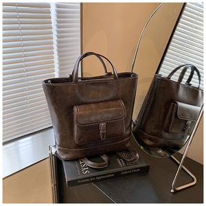 Detail of deep brown PU leather tote bag with white stitching and retro magnetic pocket