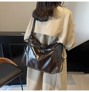 Close-up of dark brown glossy leather tote bag with contrast stitching on beige trench coat