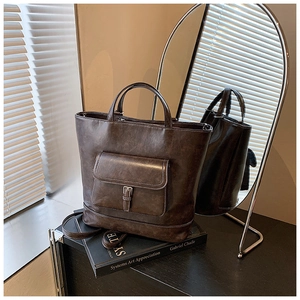 Detail of dark brown vintage tote bag with metal buckle pocket on art books