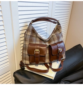 Detail of retro plaid wool shoulder bag featuring dual brown leather pockets and metal buckles