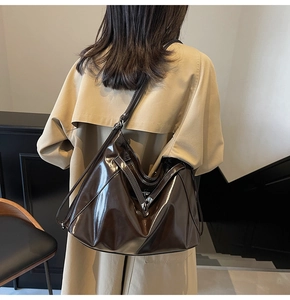 Close-up of a glossy coffee brown tote bag showing smooth faux leather texture and straps