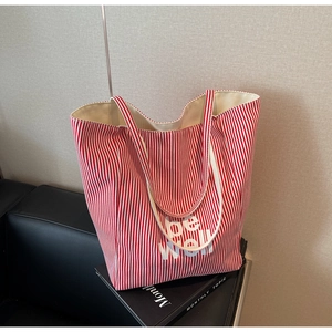 Detail der rot-weiß gestreiften Canvas-Einkaufstasche mit 'be well' Slogan auf Sofa