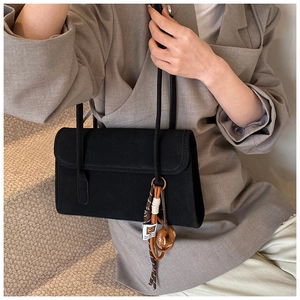Detail of a vintage black suede shoulder bag with a stylish woven rope tassel charm