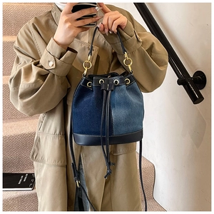 Detail of color-block denim bucket bag with drawstring closure and golden hardware