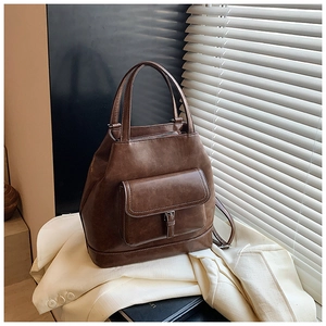 Close-up of vintage brown leather tote bag with contrast stitching and metal buckle