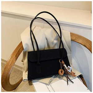 Detail of vintage matte black shoulder bag with unique wooden ring and woven cord pendant