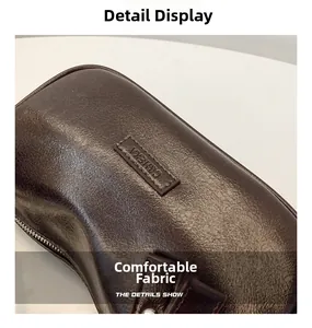 Gros plan sur la texture du cuir marron foncé et le logo de ce sac à bandoulière chic
