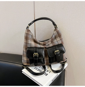 Detail of hobo bag featuring plaid fabric, black leather pockets, and gold metal buckles