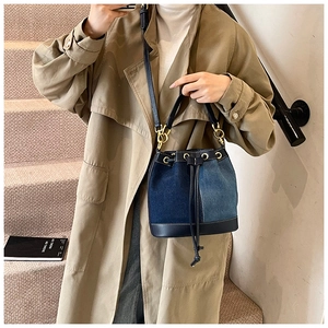 Detail view of denim bucket bag showing patchwork texture and gold-tone drawstring hardware