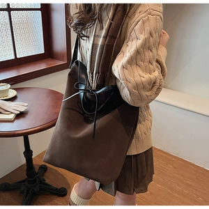 Vue détaillée du sac cabas en daim marron foncé avec bordure en cuir et nœud décoratif