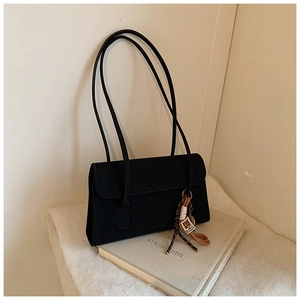 Detail of a black matte rectangular shoulder bag featuring a braided rope pendant detail