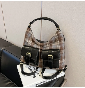 Detail of British plaid shoulder bag with black leather pockets and gold buckles