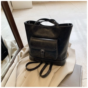 Detail of black faux leather backpack featuring white contrast stitching and metal buckle