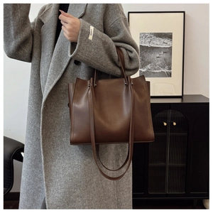Detail shot of a dark brown leather tote bag showing smooth texture and large capacity