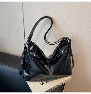 Detail of black glossy PU leather hobo bag with contrast white stitching and strap