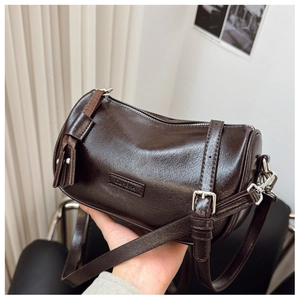 Gros plan d'un sac en cuir ciré marron foncé avec des boucles argentées et logo