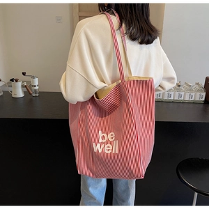 Detailansicht der gestreiften Canvas-Einkaufstasche mit be well Aufdruck im Café-Ambiente