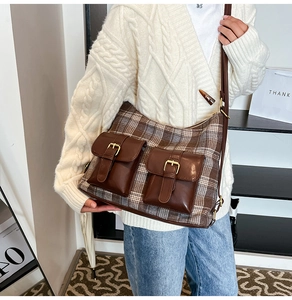 Brown plaid crossbody bag with twin front pockets worn by a model in a knit cardigan