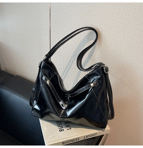 Gros plan sur un sac cabas noir brillant avec surpiqûres blanches et boucle en métal argenté