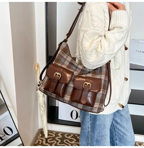 Detail view of a vintage plaid shoulder bag with dual front pockets on a model