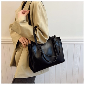 Detail view of the black minimalist tote bag with metal studs and double shoulder straps