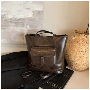 Detail of dark brown leather tote with white contrast stitching and silver buckle accent