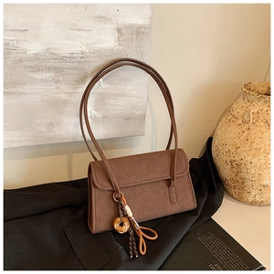Detailed view of a vintage brown matte suede shoulder bag on a black blazer background