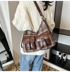 Detail view of a vintage plaid underarm bag with decorative leather pockets and gold buckles