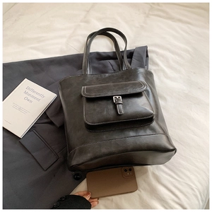 Detail of dark grey tote bag with contrast stitching and metal buckle pocket
