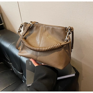 Dettaglio del manico a pieghe della borsa a secchiello marrone con anello argento