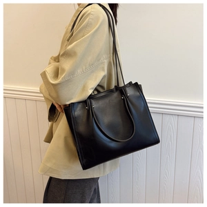 Side view of black large capacity tote bag with dual straps worn by a model