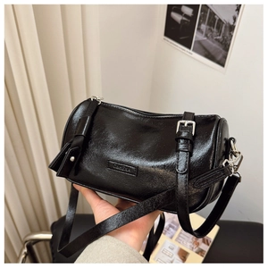 Détails d'un sac bandoulière cylindrique noir brillant avec accessoires en métal argenté