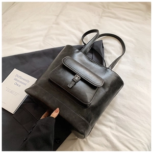 Detailed view of the black retro tote bag with front buckle pocket on soft white fabric