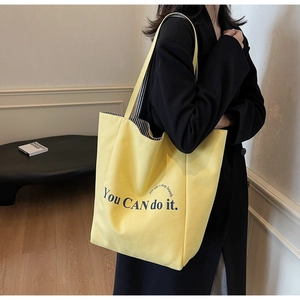 Detail der gelben Canvas-Tasche mit fettgedrucktem Schriftzug und gestreiftem Futter