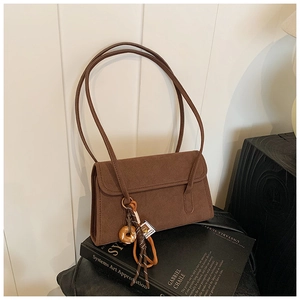 Detail of dark brown matte suede shoulder bag with creative donut pendant on art book