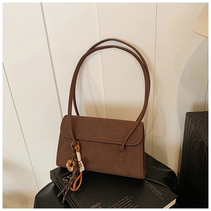 Detail of dark brown suede shoulder bag with donut charm on hardcover books