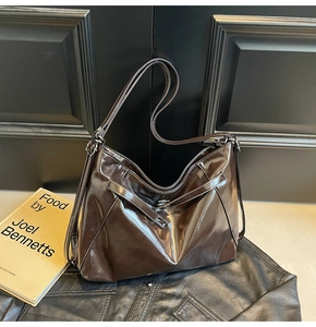 Detail of coffee brown tote bag in glossy oil wax leather with metallic buckle accents