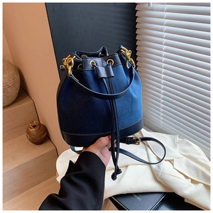 Detail of navy blue patchwork bucket bag with drawstring closure and gold hardware