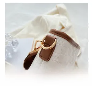 Detailed macro view of the gold-tone metal hook and checkered embossed leather on the bag