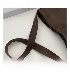 Detail view of deep brown vintage wrinkled leather texture and stitching on the bucket bag