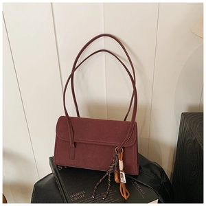 Detailed close-up of dark red matte suede shoulder bag with fringe tassel and braided cord