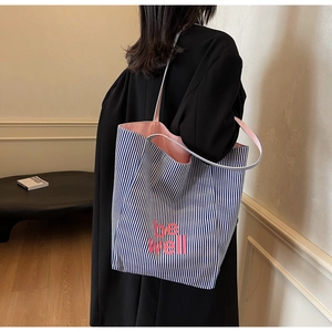 Detailansicht einer blau-weiß gestreiften Canvas-Tasche mit rosa be well Aufschrift