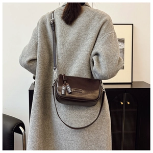 Détail d'un sac polochon en cuir marron foncé avec grain litchi et bandoulière réglable