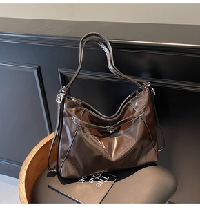Detailed close-up of dark brown glossy leather tote bag with silver metal buckles