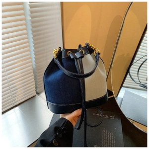 Detailed view of drawstring bucket bag with contrast stitching and golden hardware